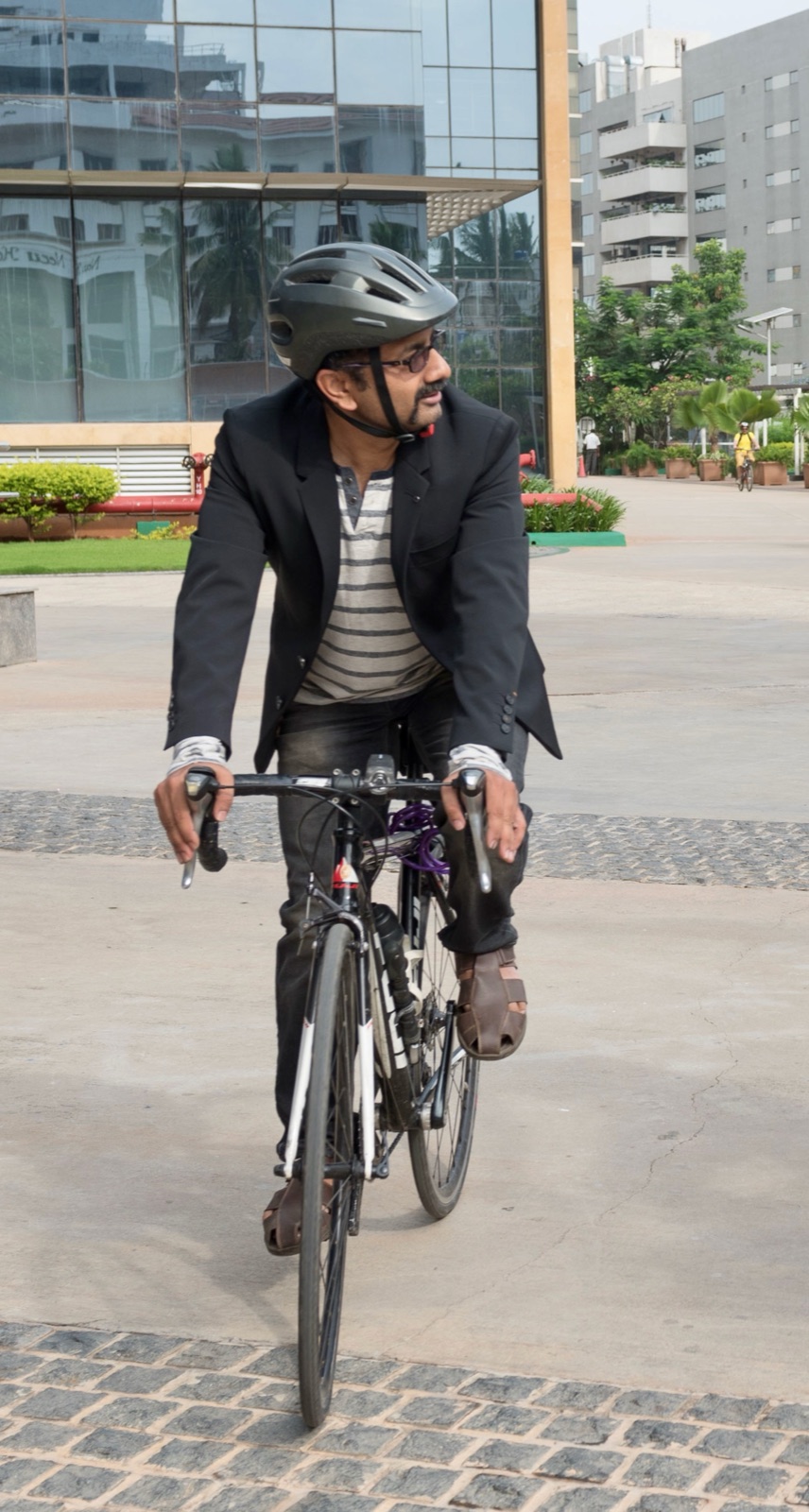 Sathya Sankaran cycling through a Bengaluru tech park in helmet and blazer