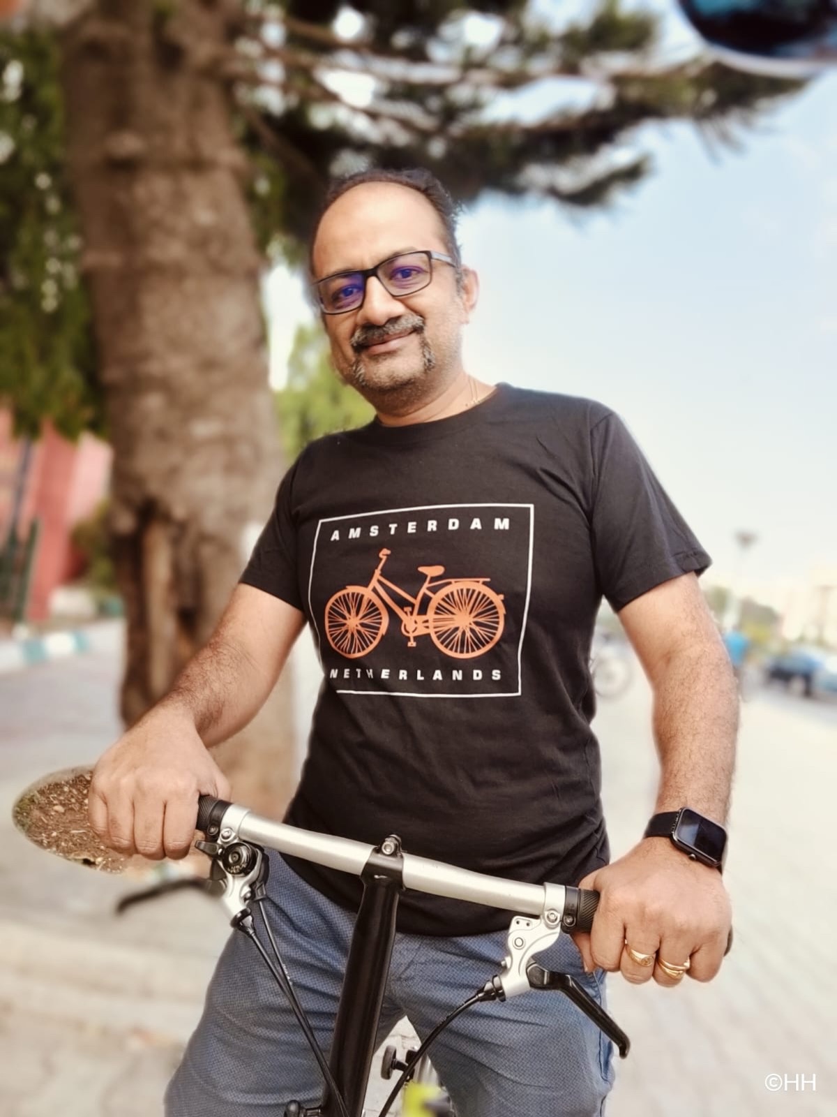Sathya Sankaran in Amsterdam cycling t-shirt with his Brompton folding bike