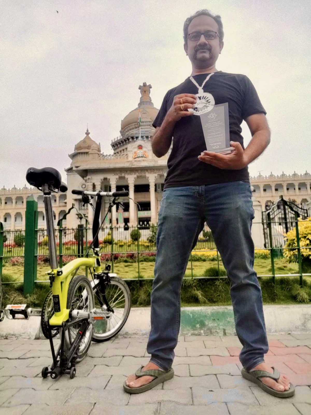 Sathya Sankaran with his yellow Brompton folding bike at Vidhana Soudha, Bengaluru